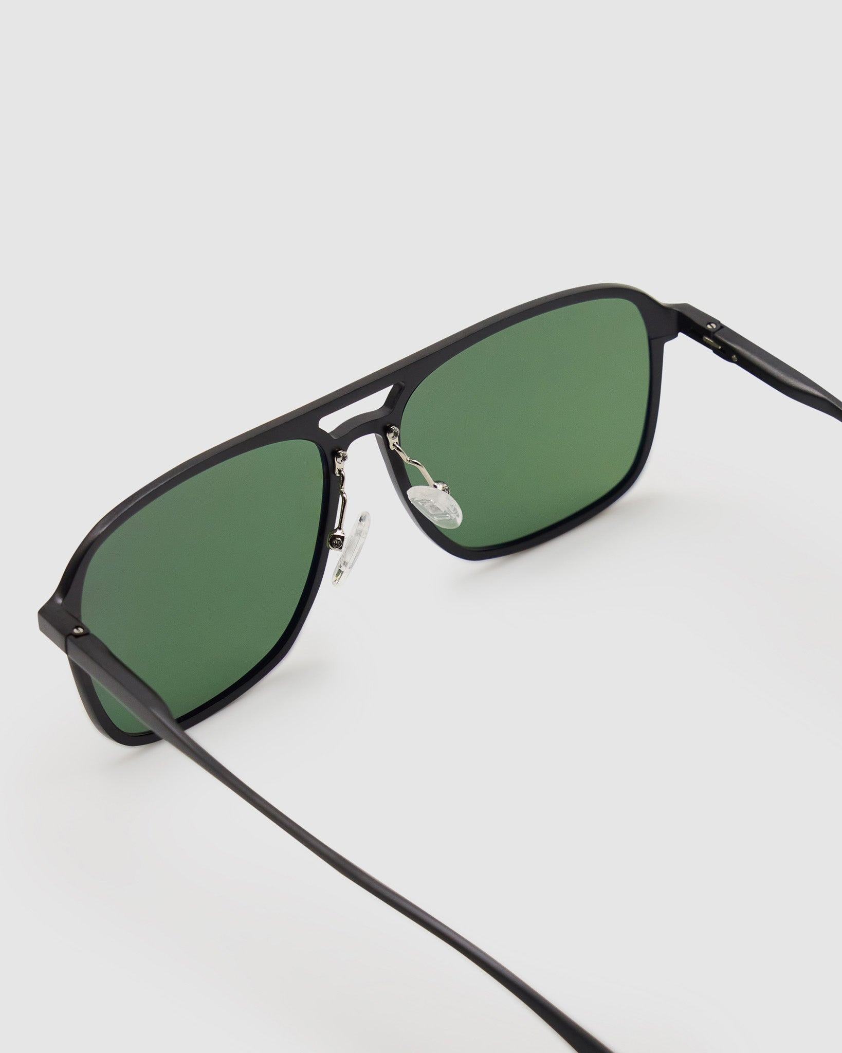Oscar Sunglasses  by Tribu Eyewear — Metallic black aluminium aviator, green polarised lens, detailed view on light grey background. 