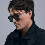 Oscar Sunglasses  by Tribu Eyewear — Metallic black aluminium aviator, green polarised lens, male model  light grey background. 