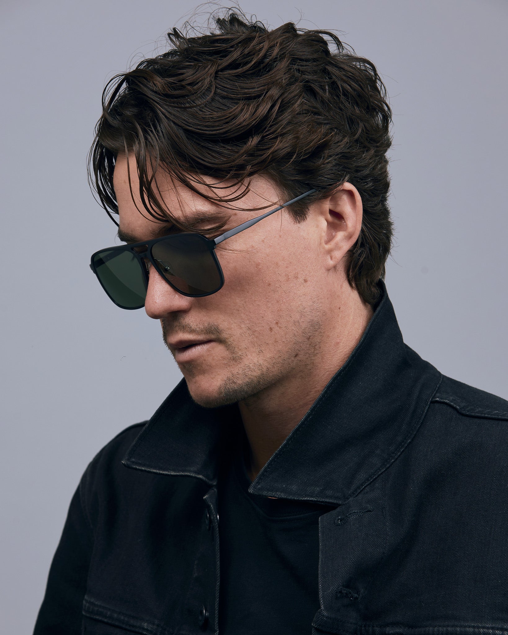 Oscar Sunglasses  by Tribu Eyewear — Metallic black aluminium aviator, green polarised lens, male model  light grey background. 