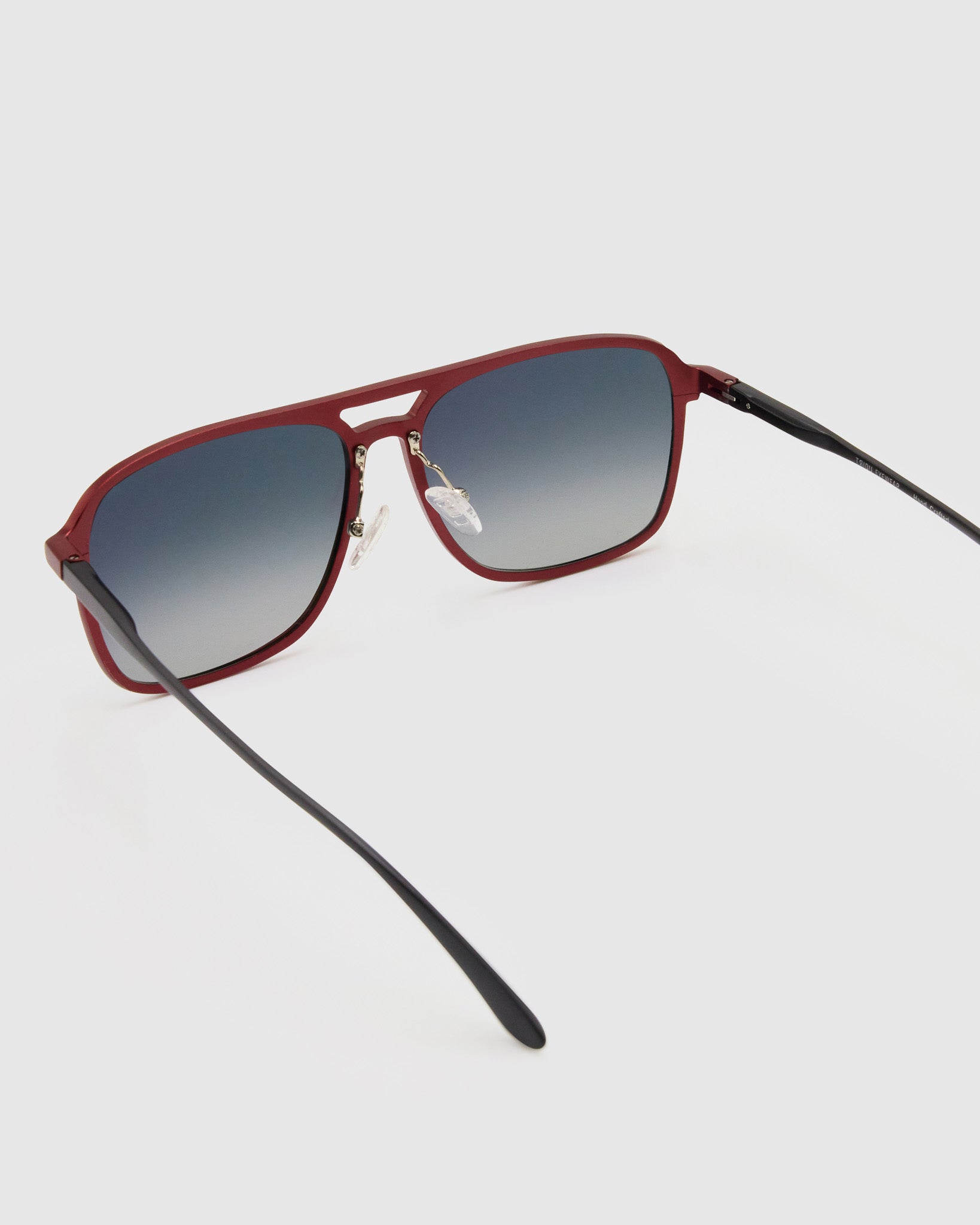Oscar Polarised Sunglasses by Tribu Eyewear —   Metallic Burgundy Aluminium Aviator frame, grey grad lens, detailed view light grey background.