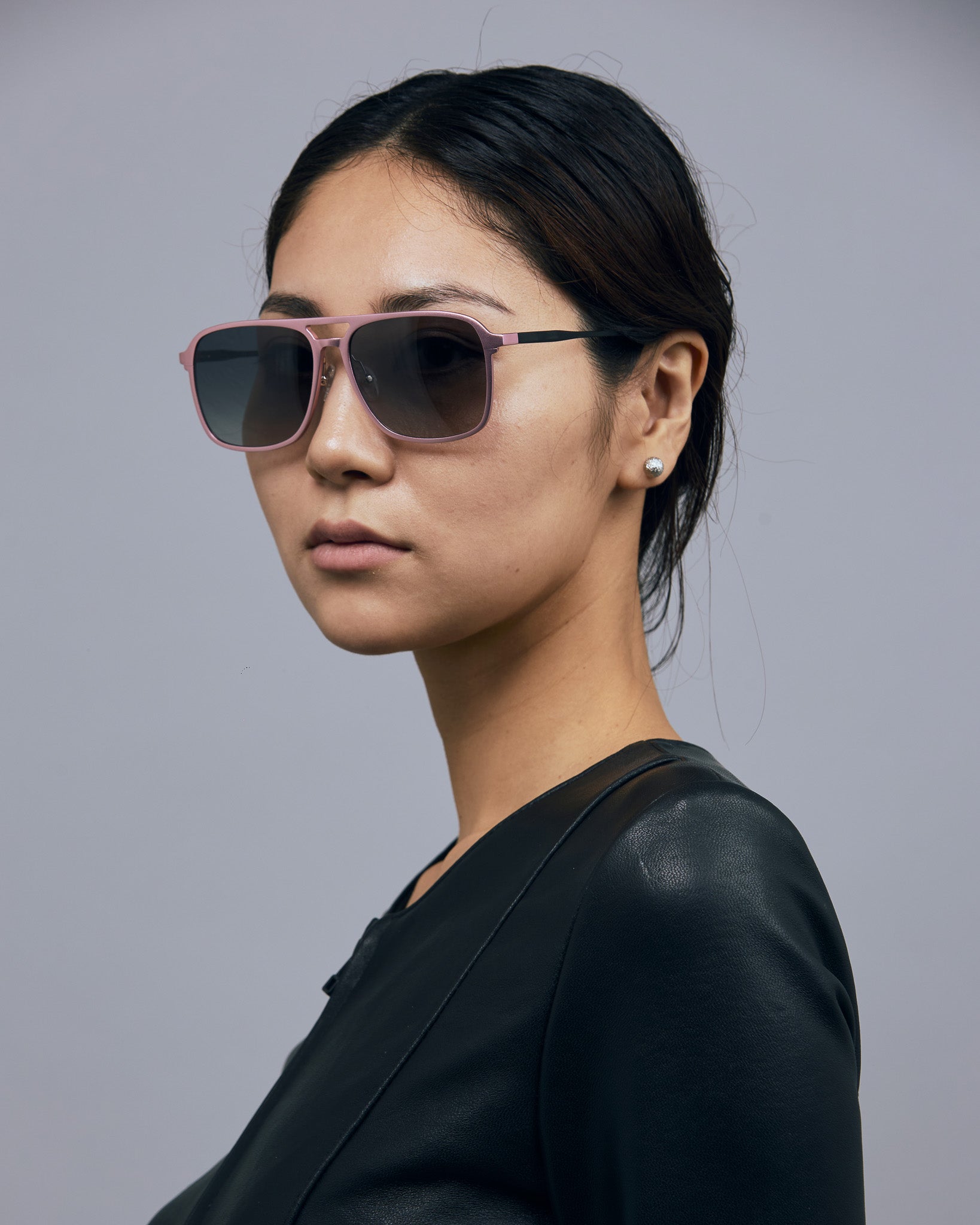 Oscar Sunglasses  by Tribu Eyewear — Metallic pink aluminium aviator, grey grad polarised lens, female model in studio. 