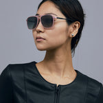 Oscar Sunglasses  by Tribu Eyewear — Metallic pink aluminium aviator, grey grad polarised lens on female model  grey background. 