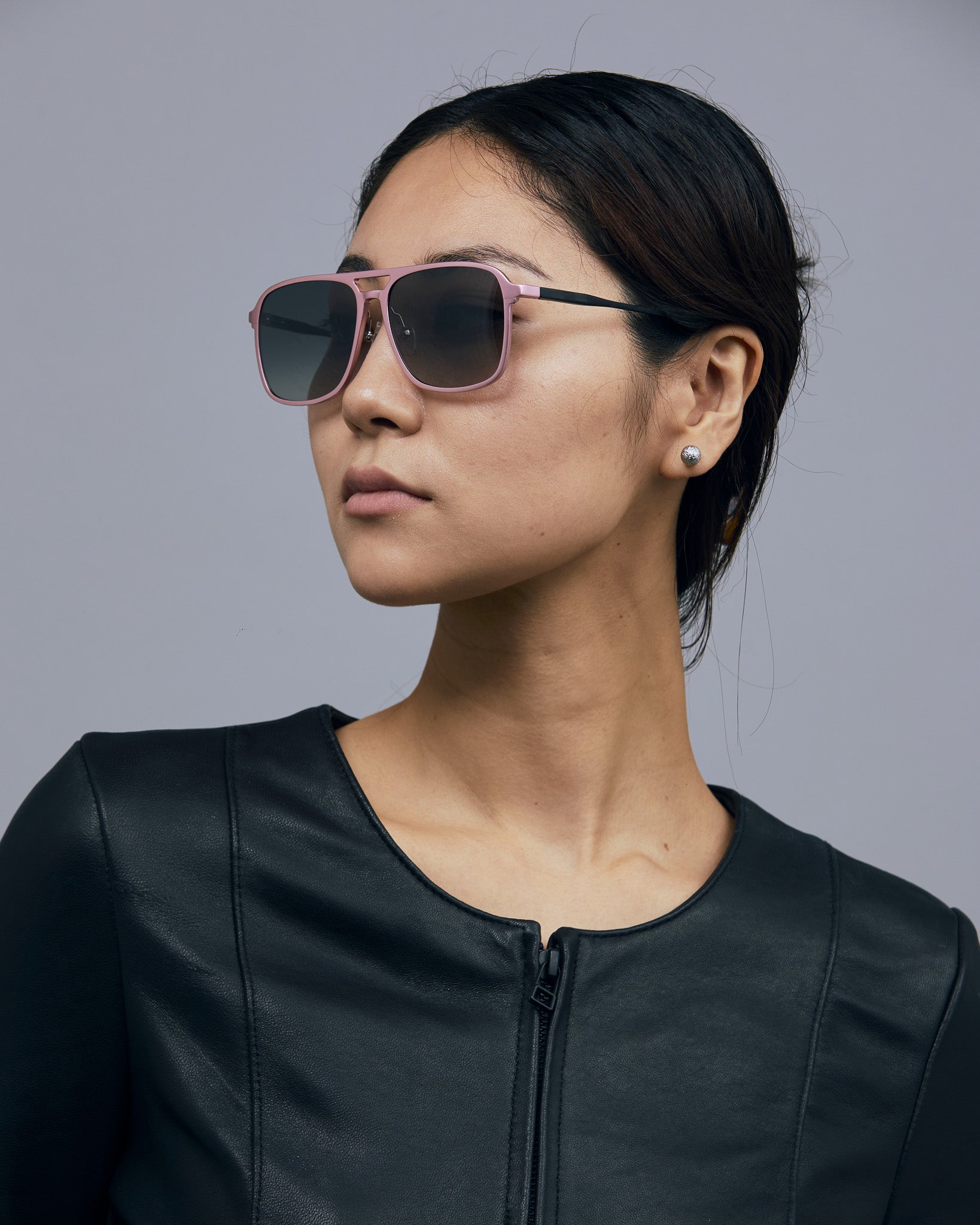 Oscar Sunglasses  by Tribu Eyewear — Metallic pink aluminium aviator, grey grad polarised lens on female model  grey background. 