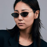 Model wearing TRIBU Nardi black and gold cat-eye sunglasses.